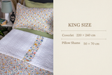 Floral bedspread with a white quilt on a bed in a bedroom setting.