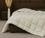Hotel-quality cotton feather filled comforter from the Signature Collection styled in a luxury bedroom with soft layered bedding and elegant neutral décor