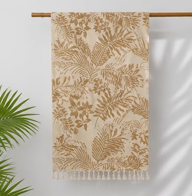 Beige towel with leaf pattern hanging on a rod against a white background