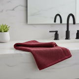 Folded burgundy towel on a light gray background