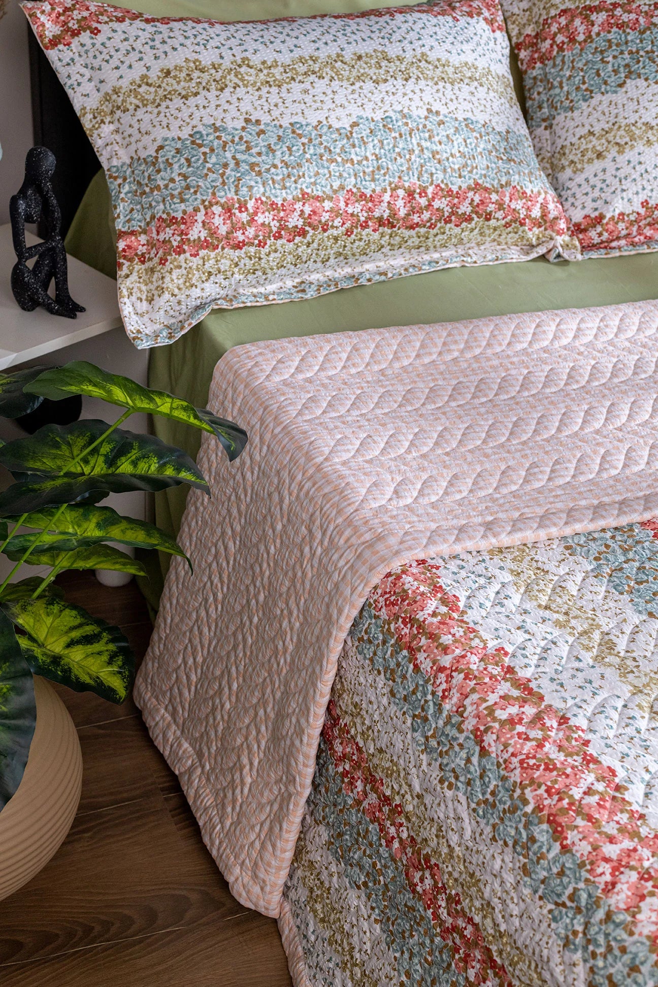 Quilted bedspread with colorful pattern on a bed in a bedroom setting.