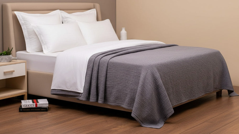 Bed with gray blanket and white pillows in a bedroom setting
