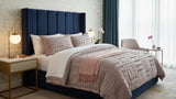 Neatly made bed with decorative pillows and a coverlet in a bedroom setting.