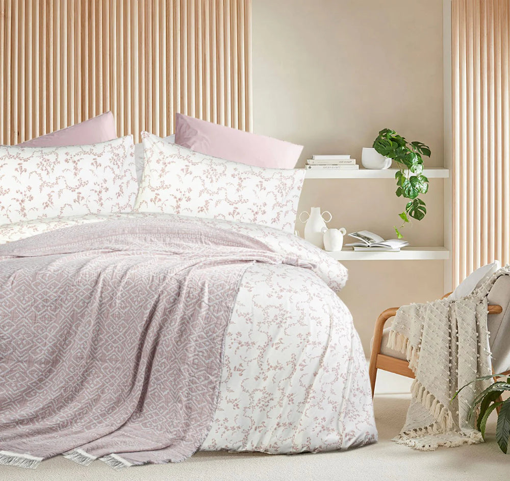 Bedroom with floral bedding and a side table with books and a plant.