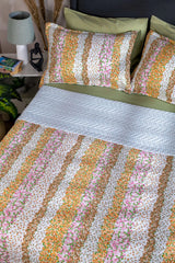Floral striped bedding set on a bed with a nightstand in the background.