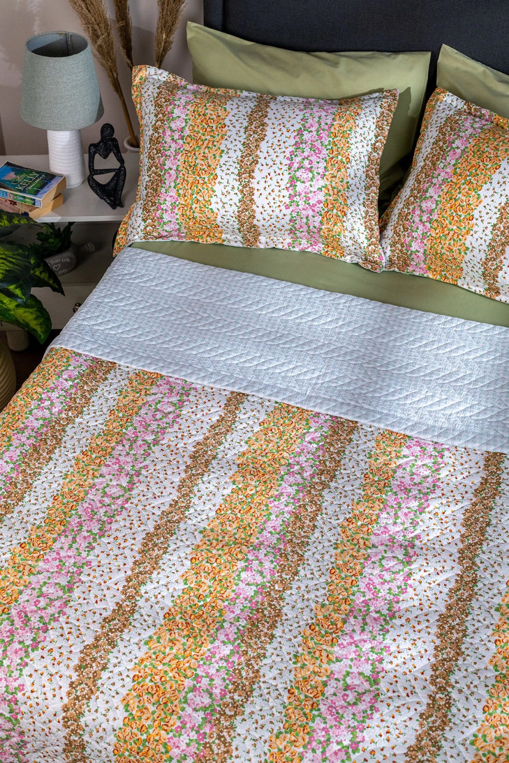 Floral striped bedding set on a bed with a nightstand in the background.